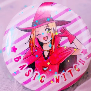 May include: A pink and white striped button with a cartoon witch wearing a red hat and a red cape. The text "BASIC WITCH" is written on the button.