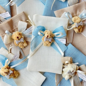 May include: Assortment of small, white and blue fabric gift bags with teddy bears and ribbons. The bags have tags that say "Hosgeldin Selim" which translates to "Welcome Selim".