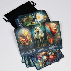 Può includere: Un set di carte oracolo con illustrazioni di un unicorno, una fenice e composizioni floreali. Le carte sono presentate con un sacchetto nero con coulisse su una superficie bianca.