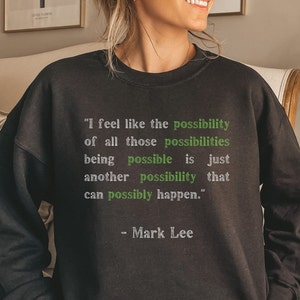 May include: Black sweatshirt with a white quote about possibility by Mark Lee. The quote reads, "I feel like the possibility of all those possibilities being possible is just another possibility that can possibly happen."