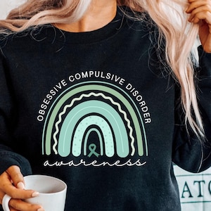 May include: Black sweatshirt featuring a green and white rainbow graphic with the text "Obsessive Compulsive Disorder awareness".