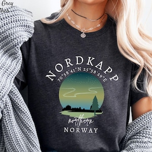 May include: Dark grey heather t-shirt with a graphic of Nordkapp, Norway, featuring a scenic landscape with a tree and the text "northern NORWAY". The shirt also includes the coordinates 70°58'41"N 25°58'29"E.