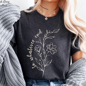 May include: Dark grey heather t-shirt with the text "to whatever end" and a floral design in a light beige color. The shirt has short sleeves and a crew neck.