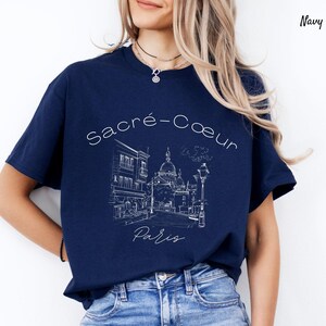 K&ouml;nnte beinhalten: Marineblaues T-Shirt mit einer wei&szlig;en Strichzeichnung der Basilika Sacr&eacute;-C&oelig;ur in Paris, Frankreich. Der Text "Sacr&eacute;-C&oelig;ur Paris" befindet sich oberhalb und unterhalb der Illustration. Das T-Shirt ist ein l&auml;ssiger Stil.