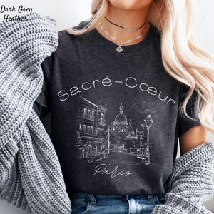 K&ouml;nnte beinhalten: Dunkelgraues meliertes T-Shirt mit einer wei&szlig;en Strichzeichnung der Basilika Sacr&eacute;-C&oelig;ur in Paris. Die W&ouml;rter "Sacr&eacute;-Coeur" und "Paris" sind ebenfalls in Wei&szlig;. Das T-Shirt hat einen Rundhalsausschnitt und kurze &Auml;rmel.