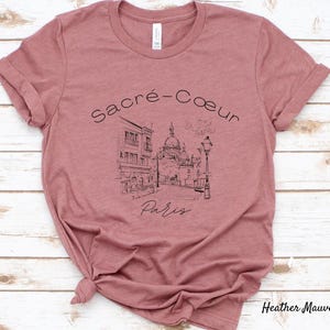 K&ouml;nnte beinhalten: Heather-Mauve-T-Shirt mit einer Schwarz-Wei&szlig;-Illustration der Basilika Sacr&eacute;-C&oelig;ur in Paris. Der Text "Sacr&eacute;-C&oelig;ur Paris" ist &uuml;ber dem Bild angeordnet. Das Shirt ist aus weichem Material.