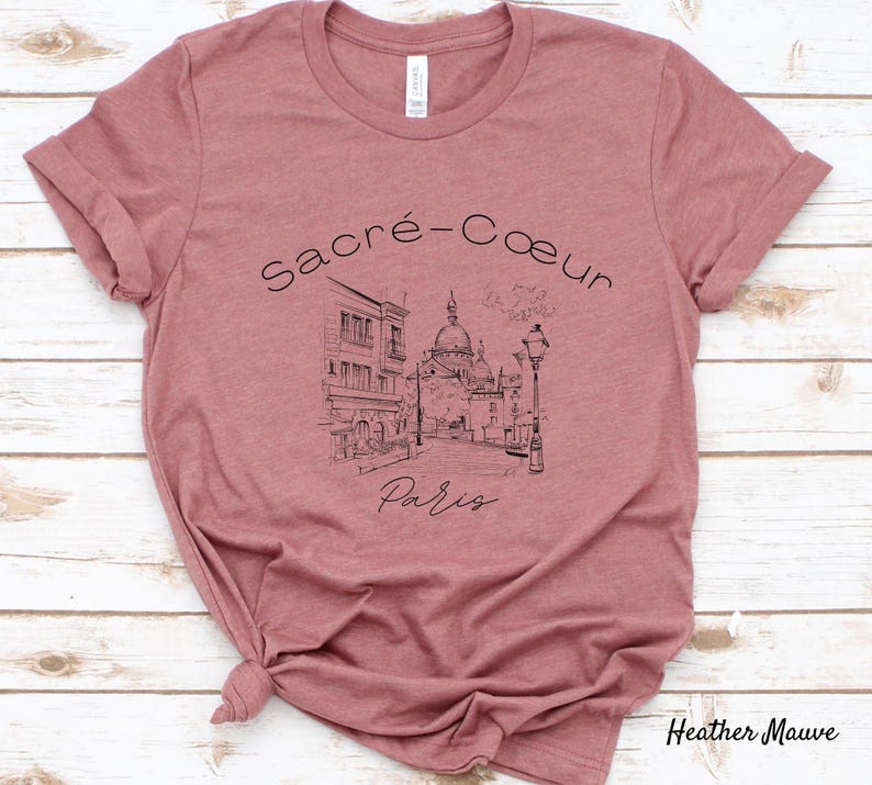 K&ouml;nnte beinhalten: Heather-Mauve-T-Shirt mit einer Schwarz-Wei&szlig;-Illustration der Basilika Sacr&eacute;-C&oelig;ur in Paris. Der Text "Sacr&eacute;-C&oelig;ur Paris" ist &uuml;ber dem Bild angeordnet. Das Shirt ist aus weichem Material.