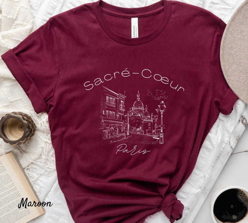 K&ouml;nnte beinhalten: Burgunderfarbenes T-Shirt mit einer wei&szlig;en Strichzeichnung der Basilika Sacr&eacute;-C&oelig;ur in Paris und dem Text "Sacr&eacute;-C&oelig;ur Paris". Das T-Shirt ist aus weichem Material und hat einen klassischen Rundhalsausschnitt.