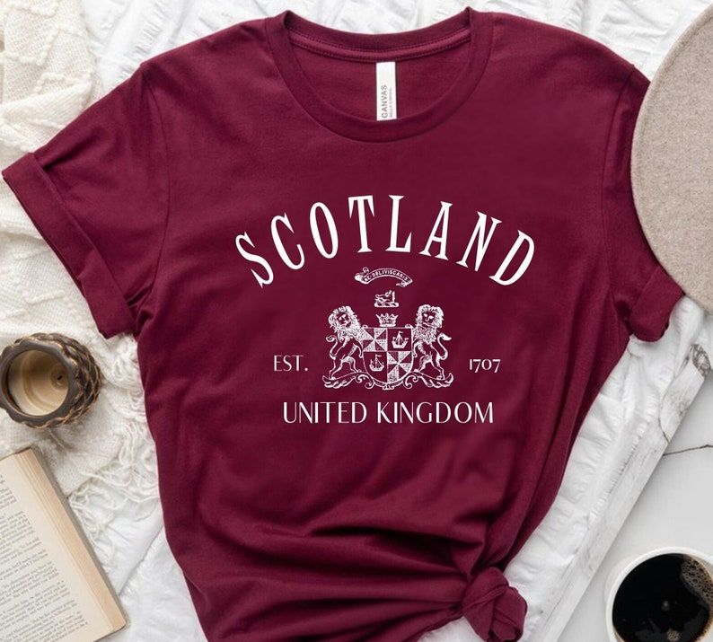 May include: Burgundy t-shirt with a white graphic of a crest and the text "Scotland Est. 1707 United Kingdom".