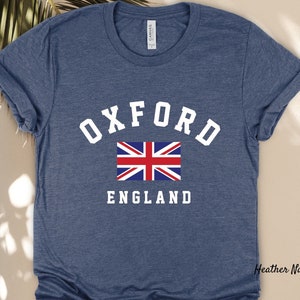 Puede incluir: Una camiseta azul marino jaspeada con texto blanco que dice "OXFORD ENGLAND" y un gr&aacute;fico de la bandera de la Uni&oacute;n Jack.