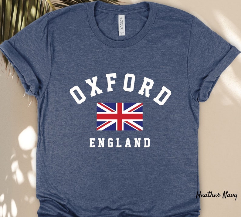 Puede incluir: Una camiseta azul marino jaspeada con texto blanco que dice "OXFORD ENGLAND" y un gr&aacute;fico de la bandera de la Uni&oacute;n Jack.