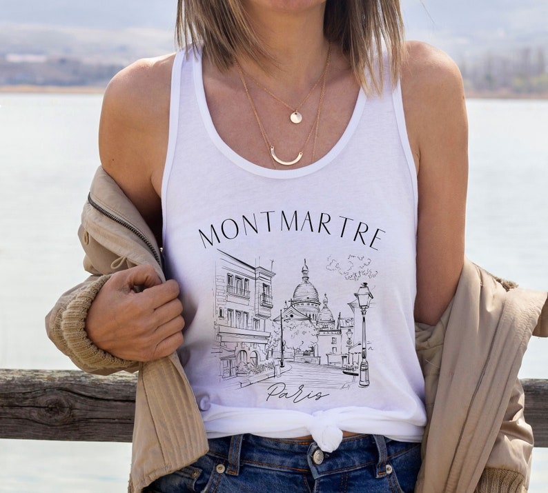 May include: White tank top with a black and white illustration of a Parisian street scene with the text "Montmartre Paris".