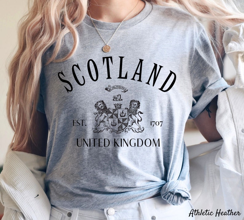 May include: Grey t-shirt with black text that reads "Scotland Est. 1707 United Kingdom" and a black and white illustration of a coat of arms.