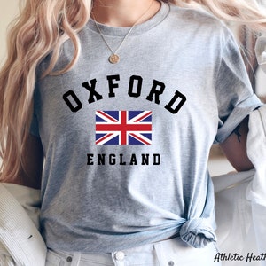 Puede incluir: Camiseta gris con texto negro que dice "Oxford England" y una bandera de la Uni&oacute;n Jack roja, blanca y azul.