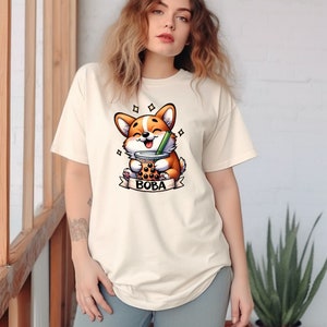 May include: A white t-shirt with a cartoon corgi dog holding a boba tea cup. The text "BOBA" is printed below the dog.
