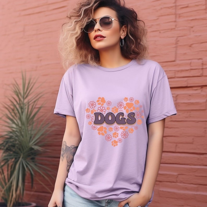 May include: A lavender t-shirt with a graphic of a heart made of paw prints and flowers. The text "DOGS" is inside the heart.