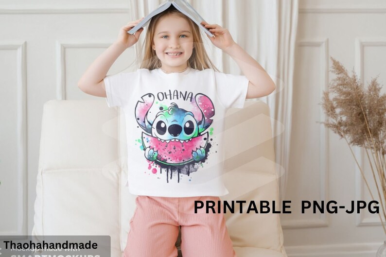 以下が含まれることがあります： リロ＆スティッチのスティッチがスイカを食べているカラフルな漫画の画像がプリントされた白いTシャツ。画像の上に「オハナ」という文字がプリントされています。シャツは子供によってモデル化されています。