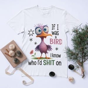 May include: White t-shirt featuring a cartoon bird with large blue eyes and an orange beak. The text on the shirt reads "If I was a bird I know who I'd SHIT on". The design includes stars and a flower.