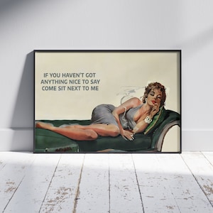 May include: A framed vintage-style print featuring a woman reclining on a green chaise lounge, wearing a gray dress. The print includes the text: "IF YOU HAVEN'T GOT ANYTHING NICE TO SAY COME SIT NEXT TO ME."