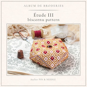 May include: A square, geometric-patterned pincushion in shades of gold, red, and white, with a dark button center. The image is from "Album de Broderies" and features the text "Étude III biscornu pattern" and "Atelier PIN & NEEDLE".