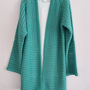 May include: A teal crochet cardigan with a long, open front and bell sleeves.