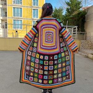 May include: A long, colorful crochet cardigan with a large, colorful square pattern in the center and smaller squares around the edges.