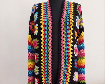 May include: A long, black crochet cardigan with a colorful granny square pattern. The cardigan has a wide, open front and long sleeves.