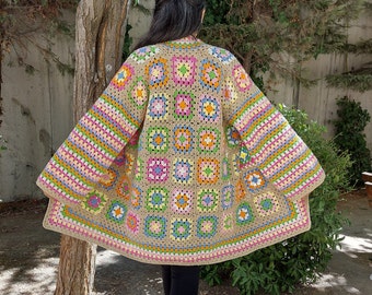 May include: A crocheted cardigan with a colorful geometric pattern. The cardigan has long sleeves and a loose fit. It is made with a variety of colors, including pink, blue, green, yellow, and orange.