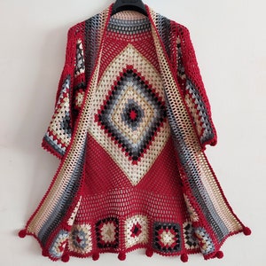 May include: A red crochet cardigan with a geometric pattern and pom-poms on the hem. The cardigan is open in the front and has a loose fit.