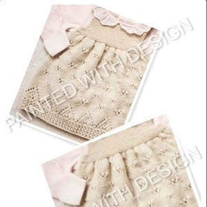 May include: A beige knitted baby dress with a delicate lace trim around the neckline. The dress has a floral pattern and is made with a soft yarn.