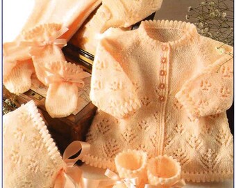 May include: A peach-colored knitted baby set featuring a long-sleeved cardigan with a button-up front, two matching bonnets, and two pairs of booties. The garments are decorated with a delicate leaf-like pattern and finished with satin ribbons.