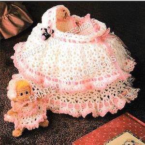 May include: A handmade crochet baby set in white and pink. The set includes a bonnet, dress, and a small doll. The dress and bonnet have pink ribbon accents and edging. The doll is also crocheted and wears a matching outfit.