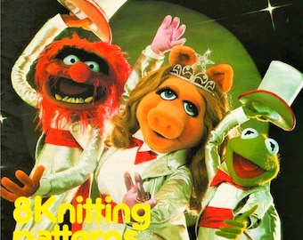 May include: A colorful illustration featuring three Muppet characters: Animal with red fur, Miss Piggy with blonde hair and a tiara, and Kermit the Frog. They wear white tuxedo jackets with red accents and top hats. Yellow text reads 8K Knitting patterns.