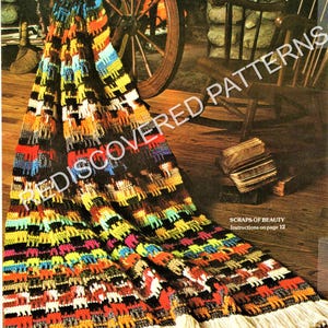May include: A crocheted blanket featuring a repeating pattern of small animal silhouettes in vibrant colors including yellow, orange, red, blue, and black. The blanket has a long white fringe along the bottom edge and includes the text SCRAPS OF BEAUTY.