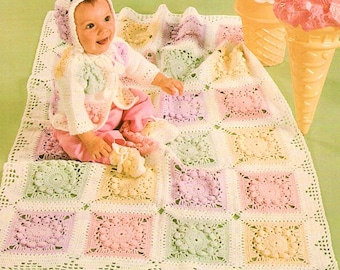 May include: A crochet baby blanket featuring a grid of square motifs in pastel pink, yellow, green, and lavender, bordered in white. The blanket is accompanied by a matching crochet bonnet and cardigan set, worn by a baby in pink pants.