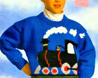 May include: A bright blue long-sleeve knit sweater featuring a white turtleneck collar and a large graphic of a black steam locomotive train with red wheels and white smoke. The bottom hem of the sweater is a solid dark green ribbed knit fabric.