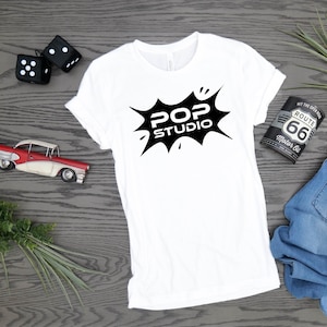May include: White t-shirt with a black graphic of a speech bubble that says "Pop Studio".