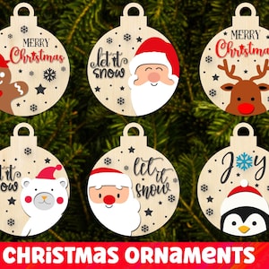 Könnte beinhalten: Sechs hölzerne Weihnachtsbaumschmuck-Designs mit verschiedenen Feiertagsmotiven. Die Ornamente sind rund und haben einen weißen Hintergrund mit bunten Illustrationen und Text. Die Designs beinhalten eine Lebkuchenfigur, den Weihnachtsmann, ein Rentier, einen Eisbären, einen Pinguin und den Spruch "Let it snow".