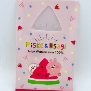 May include: Pink and white card with a watermelon design. The card features two cartoon characters, a rabbit and a bear, holding a slice of watermelon. The text "piske & usagi Juicy Watermelon 100%" is printed on the card.