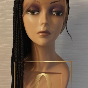 Könnte beinhalten: Eine schwarze geflochtene Perücke mit einem Spitzenfront. Die Perücke sitzt auf einem Mannequin-Kopf und hat einen Seitenscheitel. Die Perücke ist lang und glatt. Die Perücke ist handgefertigt und afro-zentrisch.