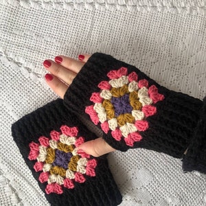 May include: A pair of black crocheted fingerless gloves with a colorful granny square design. The gloves are made with a soft yarn and have a comfortable fit.