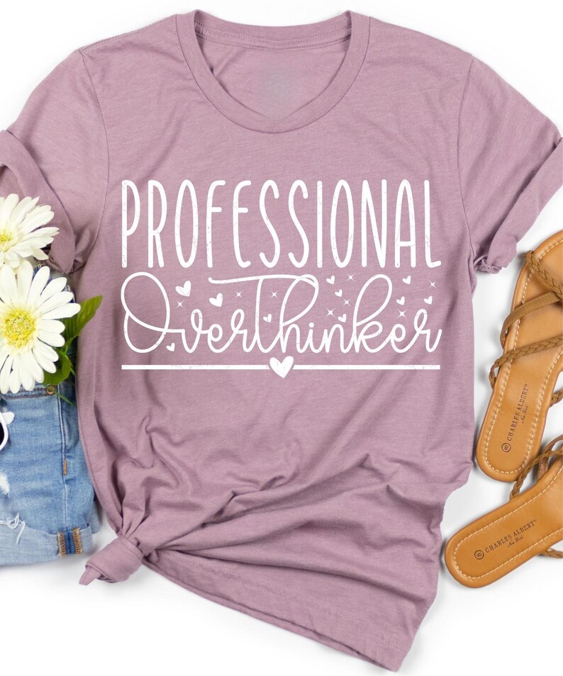a purple t-shirt with the text "Professional Overthinker" printed on it, along with a pair of sandals and some flowers.