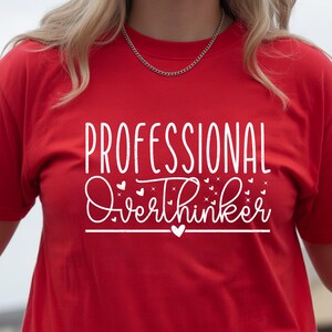 A person wearing a red t-shirt with the text "Professional Overthinker" printed on it.