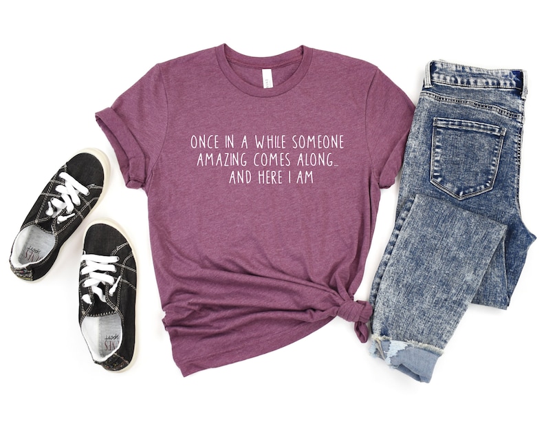 Może przedstawiać: Bordowy t-shirt z napisem "Once in a while someone amazing comes along... and here I am" w białym kolorze.