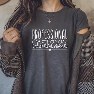 A woman wearing a gray t-shirt with the text "Professional Overthinker" printed on it.