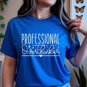 A woman wearing a blue t-shirt with the text "Professional Overthinker" printed on it.