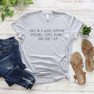 Może przedstawiać: Szary T-shirt z nadrukiem "Once in a while someone amazing comes along... and here I am." na przodzie.