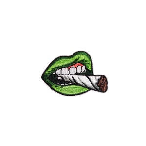 May include: Embroidered patch featuring green lips with white teeth and a lit cigarette. The patch has a white background and is designed for application on clothing or accessories.