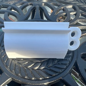 Pode incluir: Vaso de pl&aacute;stico branco com formato arredondado e uma al&ccedil;a lateral. A al&ccedil;a tem dois furos.