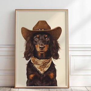 May include: A framed print featuring a dachshund dog dressed in a brown cowboy hat and a patterned bandana. The dog has long, brown fur and is looking directly at the viewer. The artwork is set against a neutral background.